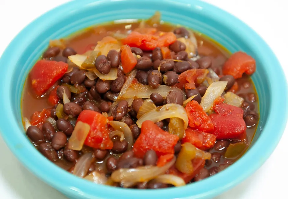 Black bean soup with tomato and onion in a teal bowl